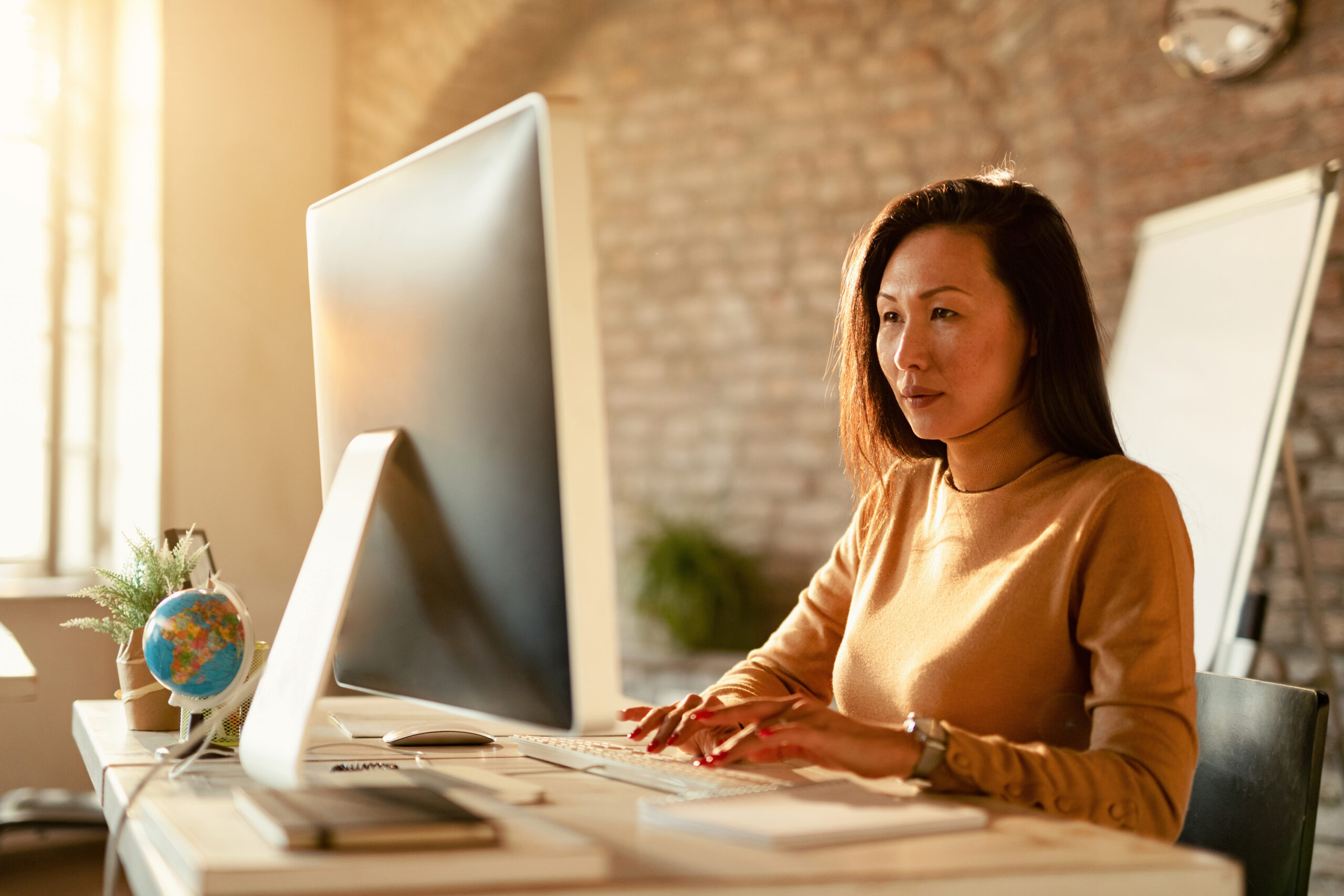 Asian businesswoman typing an e-mail on desktop PC in the office