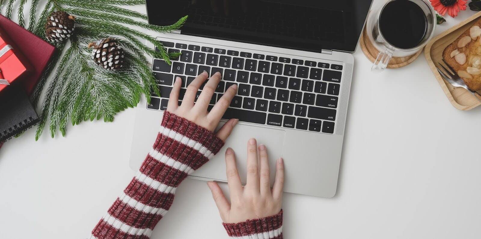 Person wearing a striped sweater typing on a laptop, surrounded by decor and snack