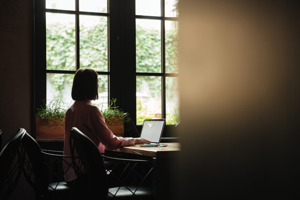 Back view of brunette woman sitting by table near window